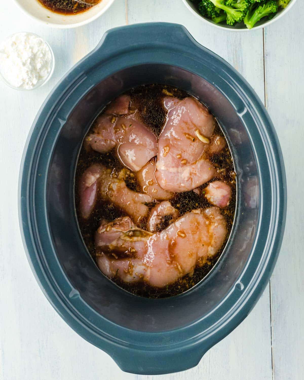 chicken in a crockpot with sauce over the top