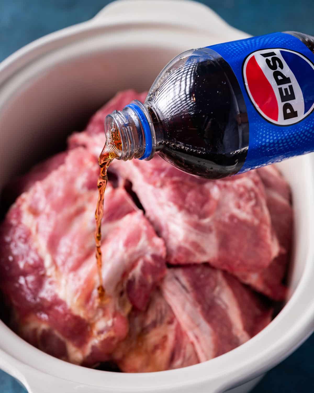 pouring pepsi over ribs in a slow cooker