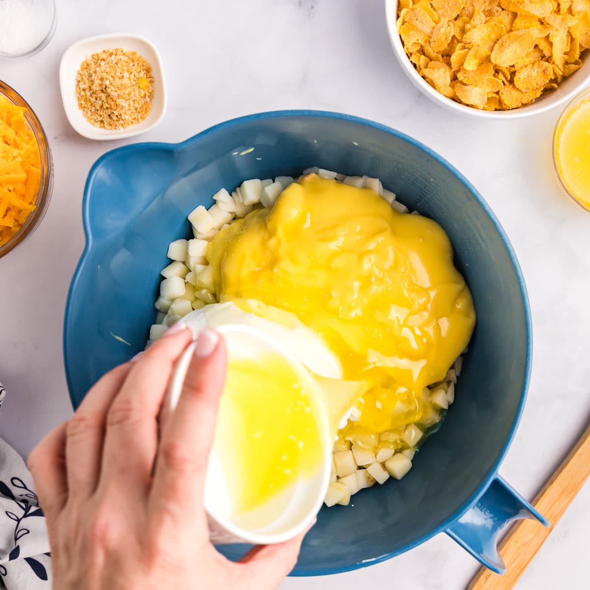 pouring melted butter over creamy potatoes in a bowl