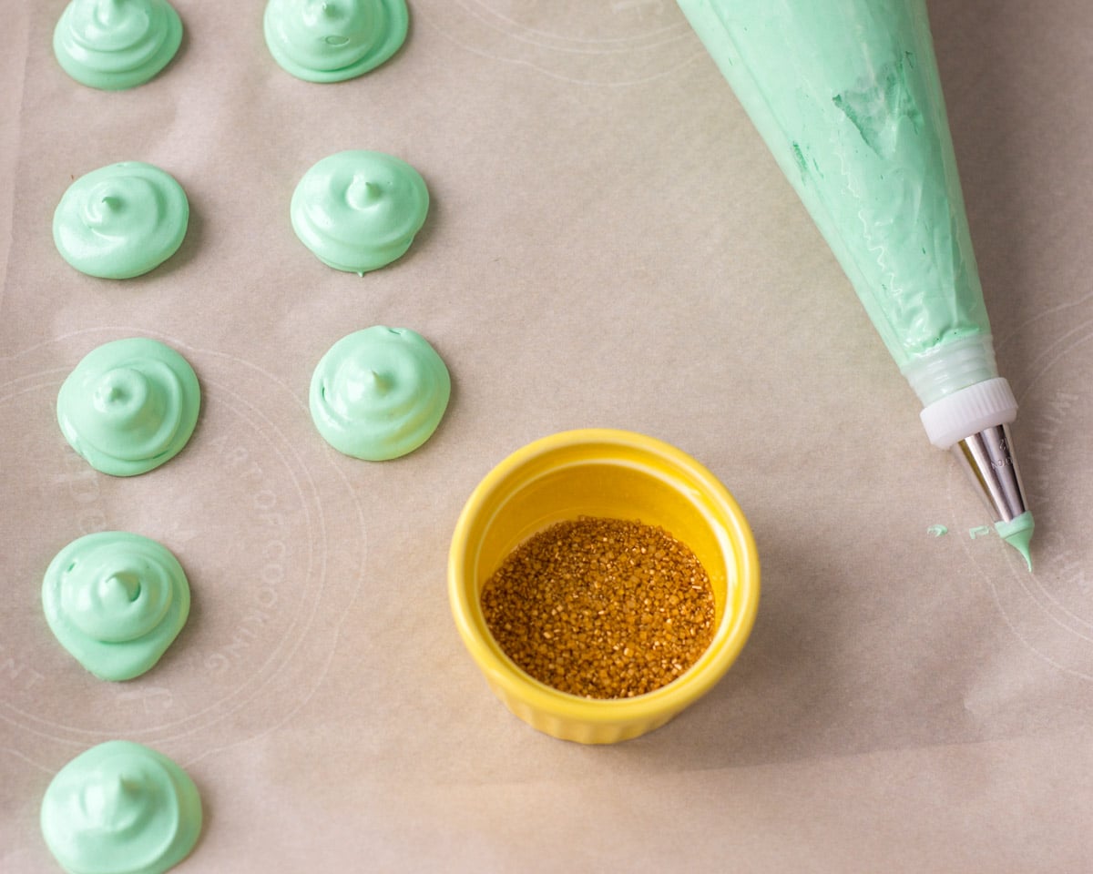 piping green meringue on parchment paper