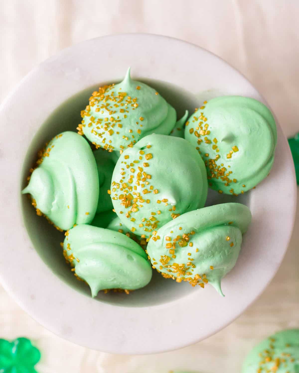 a glass bowl of green meringue cookies