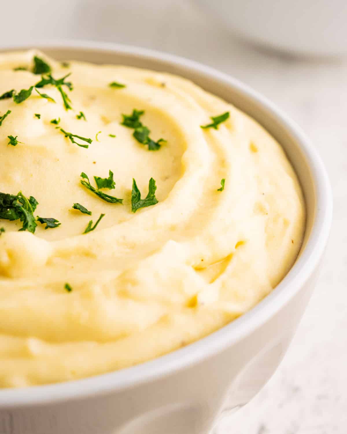 closeup of a bowl of creamy mashed potatoes with fresh parsley