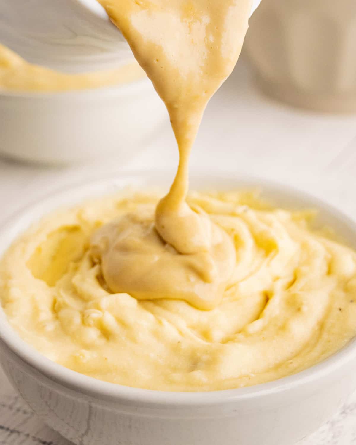 pouring gravy over a bowl of mashed potatoes