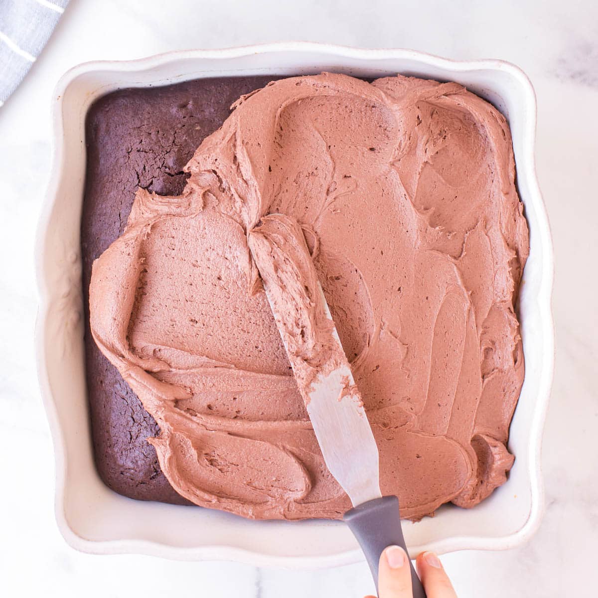 spreading frosting on a chocolate cake