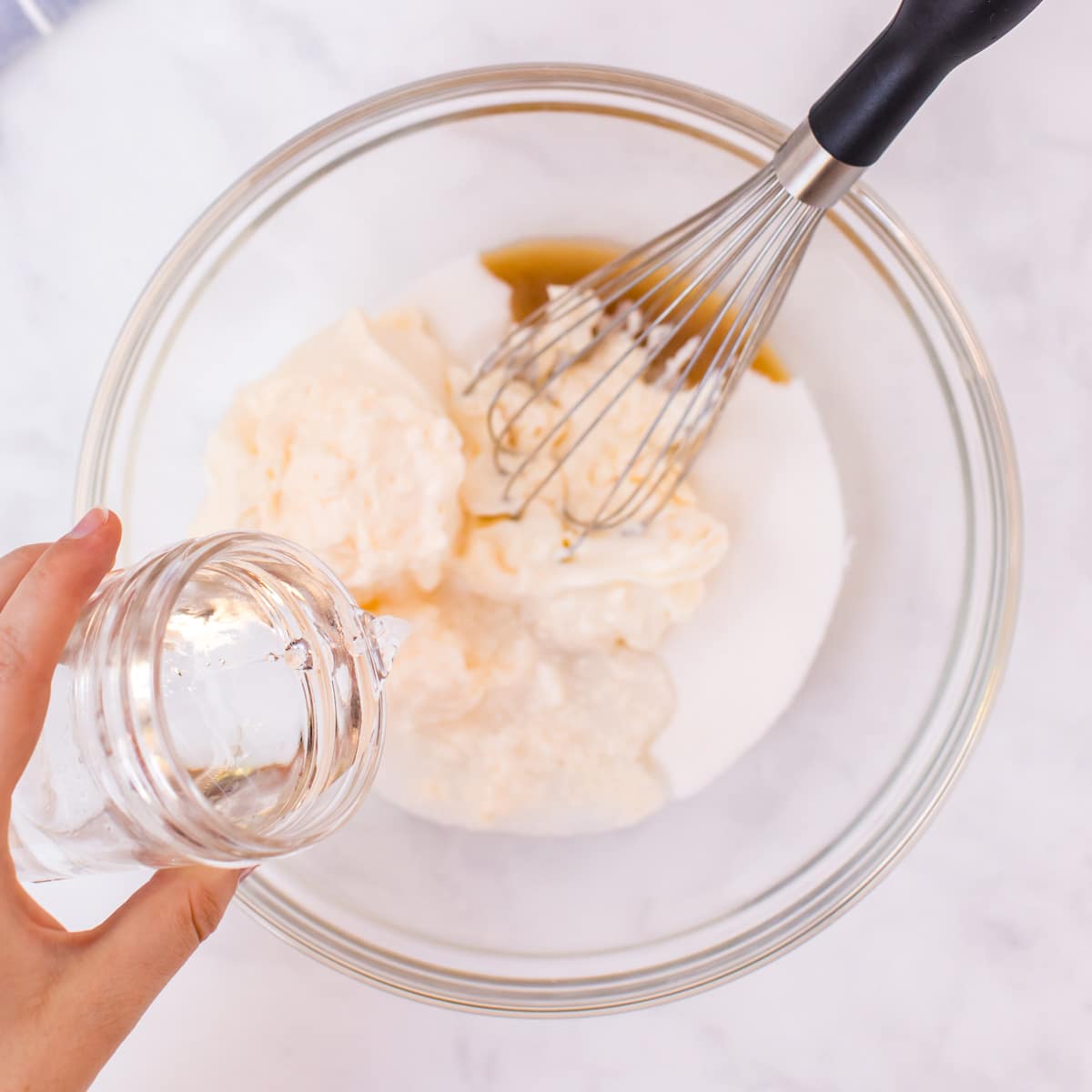 pouring water into a glass bowl with wet ingredients