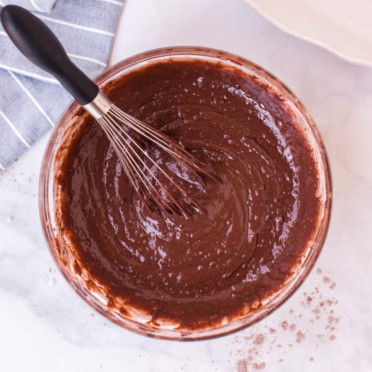 chocolate cake batter in a bowl with a whisk