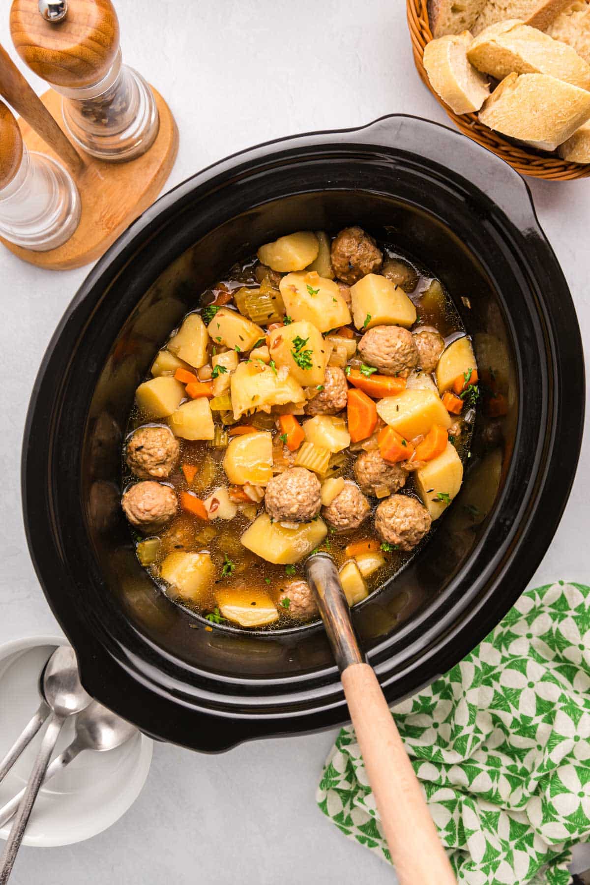 overhead view of meatball soup with potatoes on a table