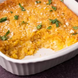 street corn casserole in a pan with spoonfuls scooped out