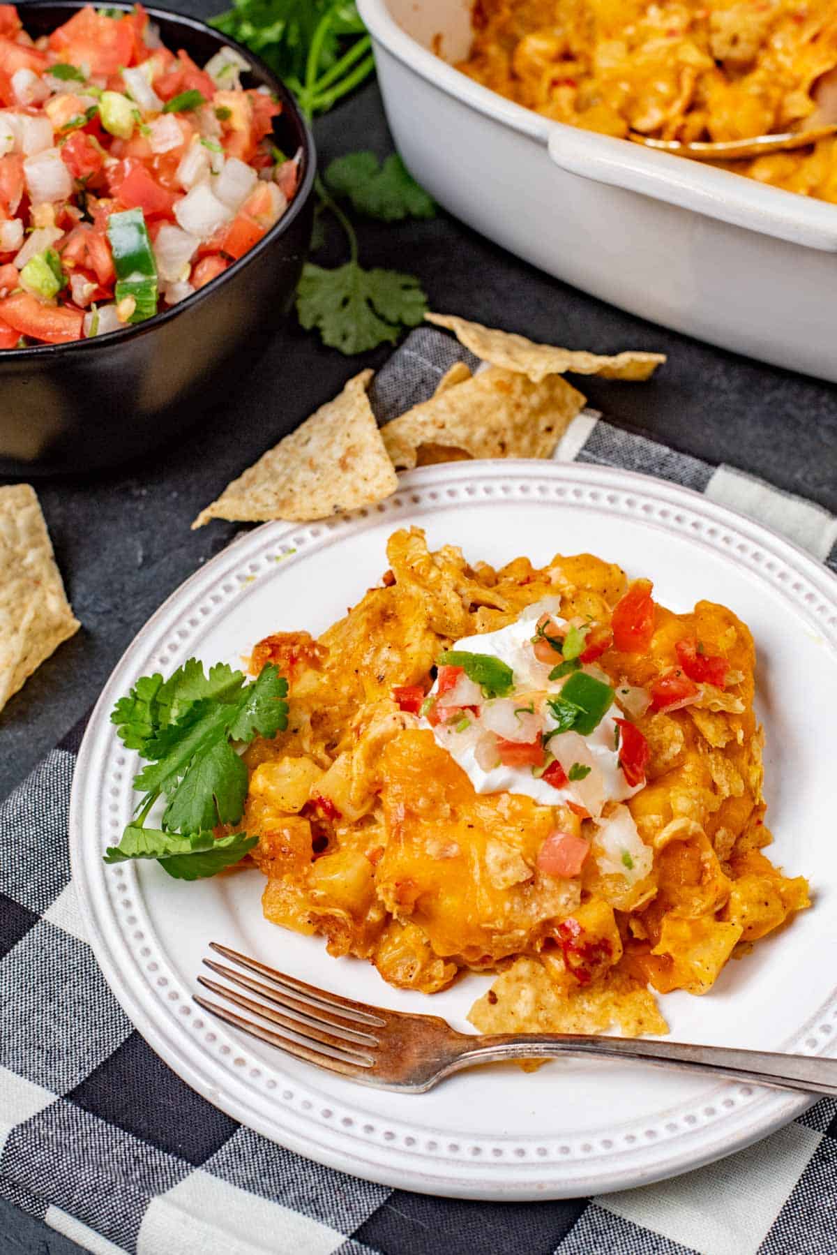 nacho chicken casserole with salsa and tortilla chips on a plate