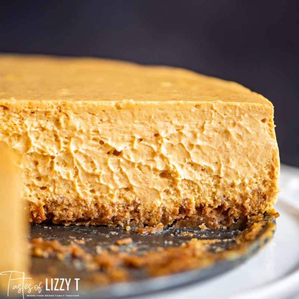 a plain pumpkin cheesecake on a plate with one bite missing