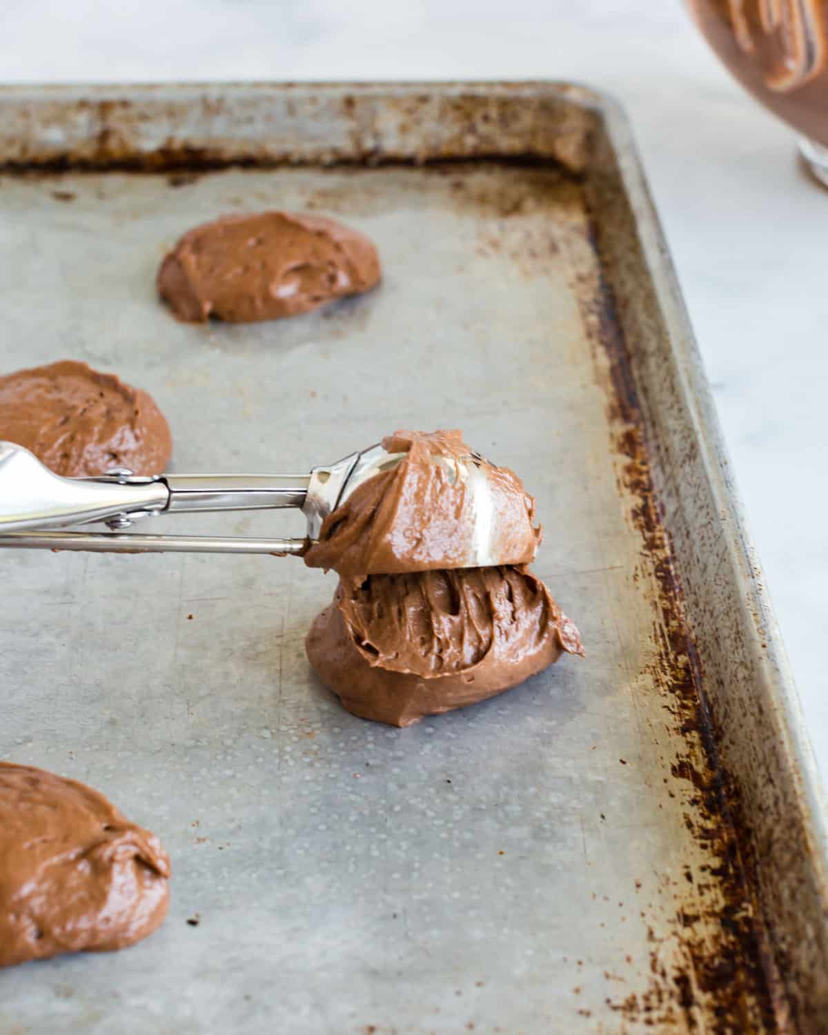 scooping cake batter on a baking sheet