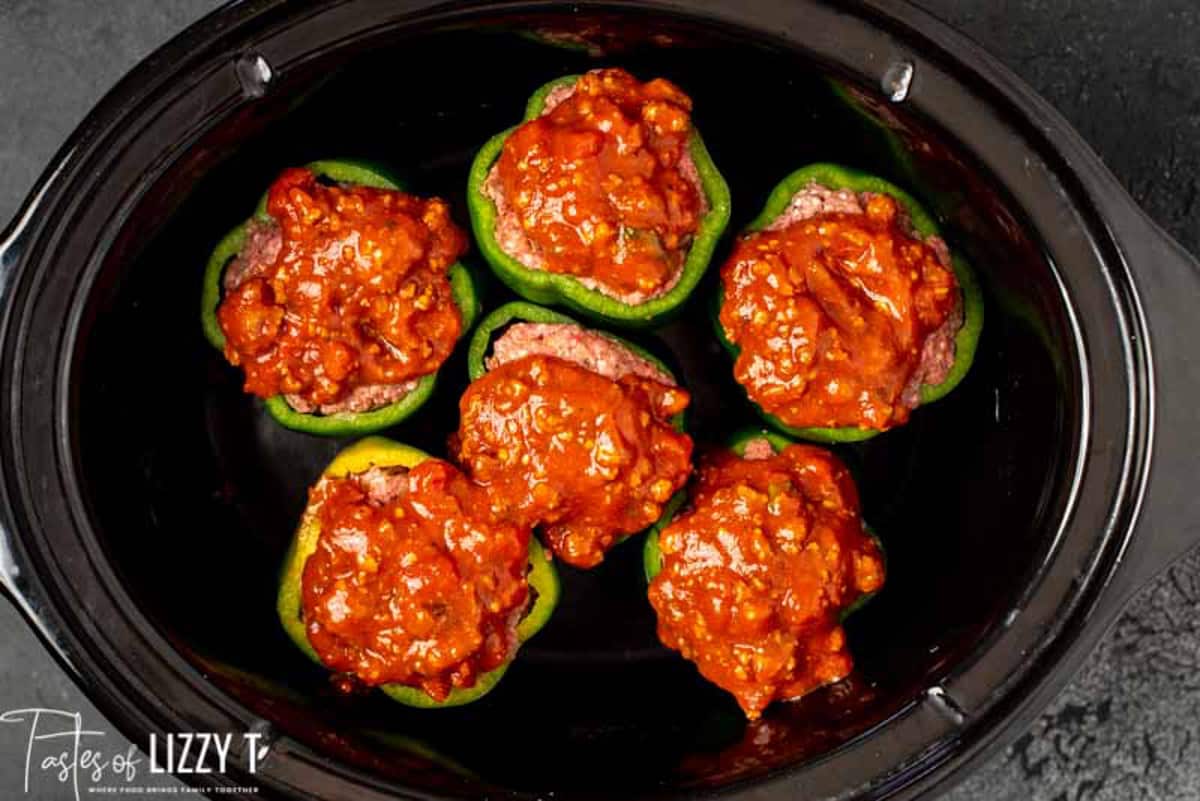 uncooked stuffed peppers in a slow cooker with spaghetti sauce