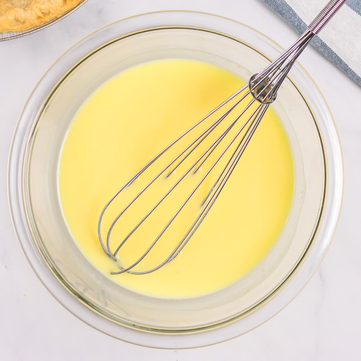 vanilla pudding in a glass bowl with a whisk