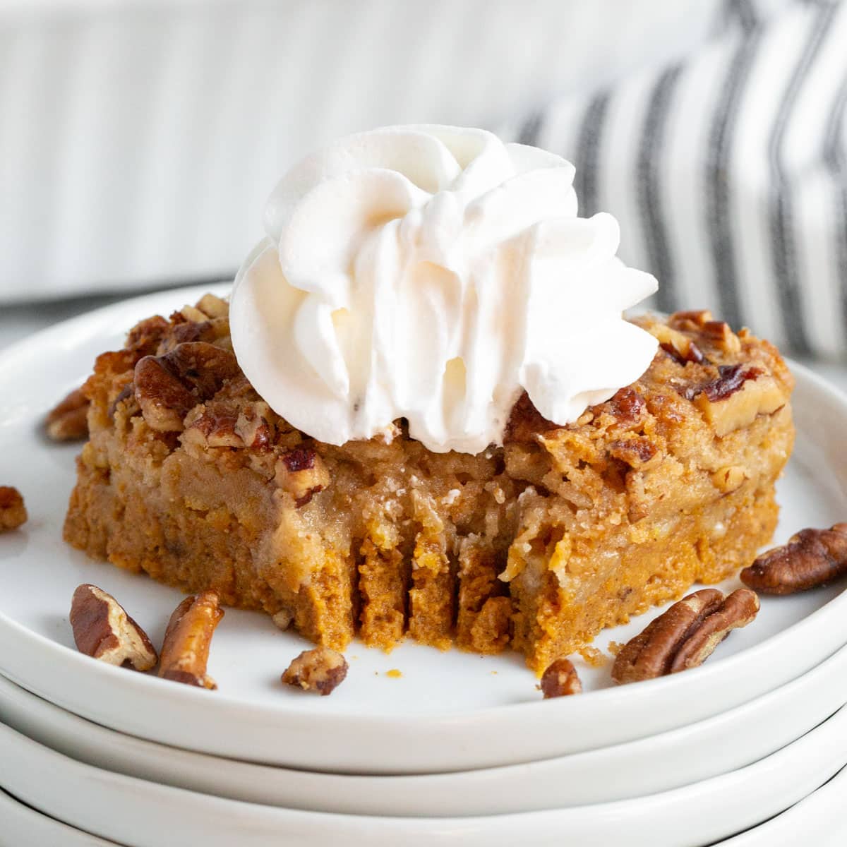 a piece of pumpkin pecan dump cake with whipped cream and a bite out