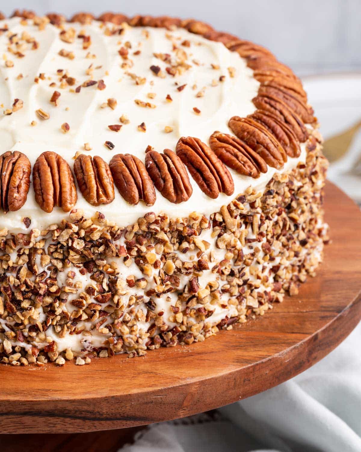 pumpkin spice cake with cream cheese frosting and pecans on a cake plate