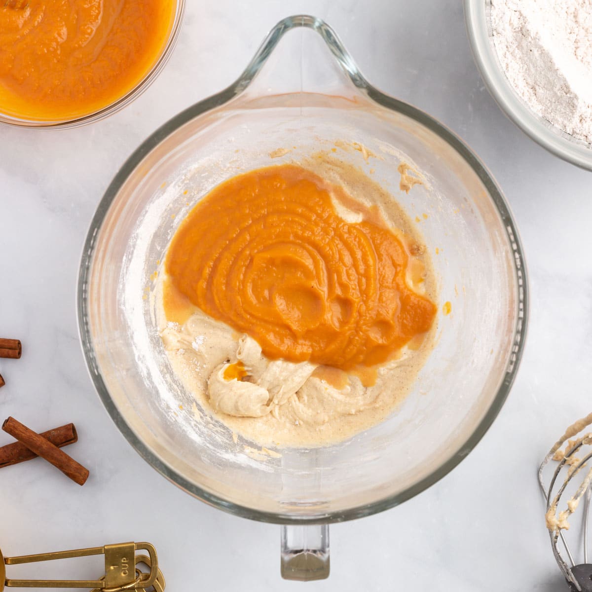 pumpkin puree over cake batter in a mixing bowl