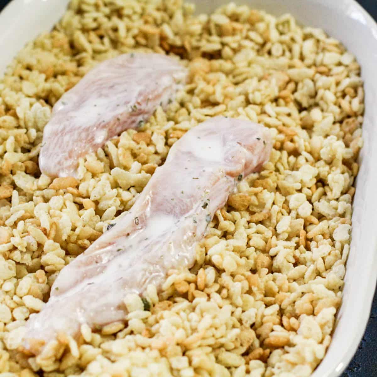 marinated chicken over rice krispies in a pan