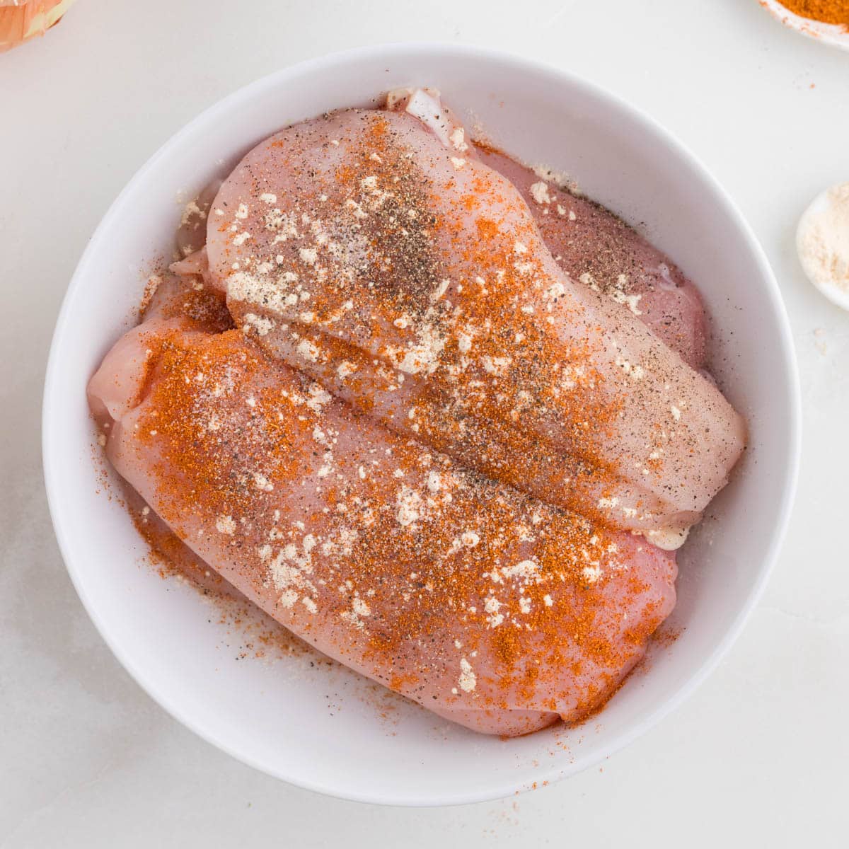 seasoned raw chicken breasts in a bowl