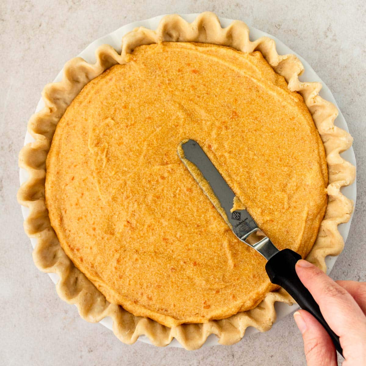 spreading sweet potato filling in a pie shell