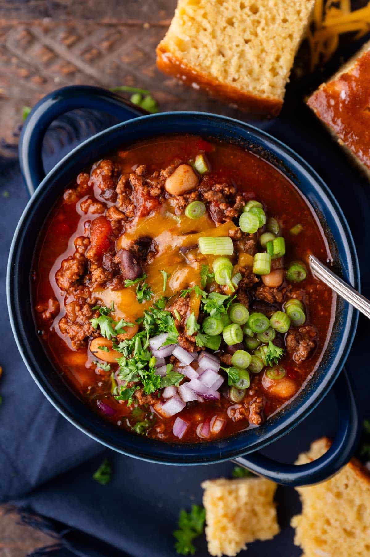 a bowl of sweet chili on a table with cornbread