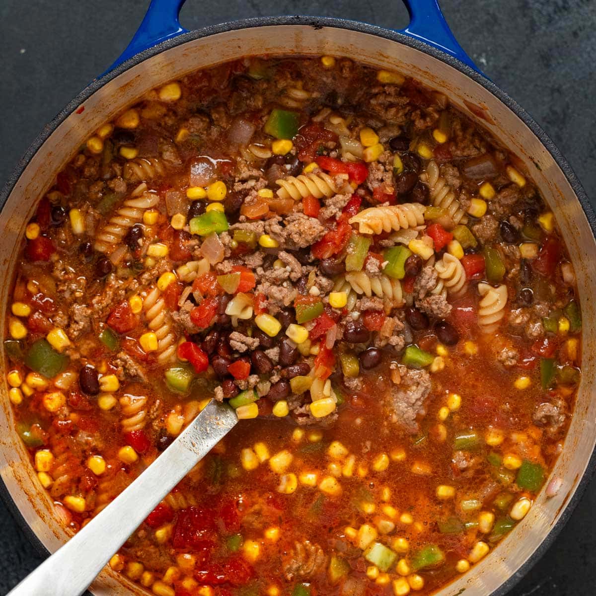 taco soup with noodles in a dutch oven with a ladle