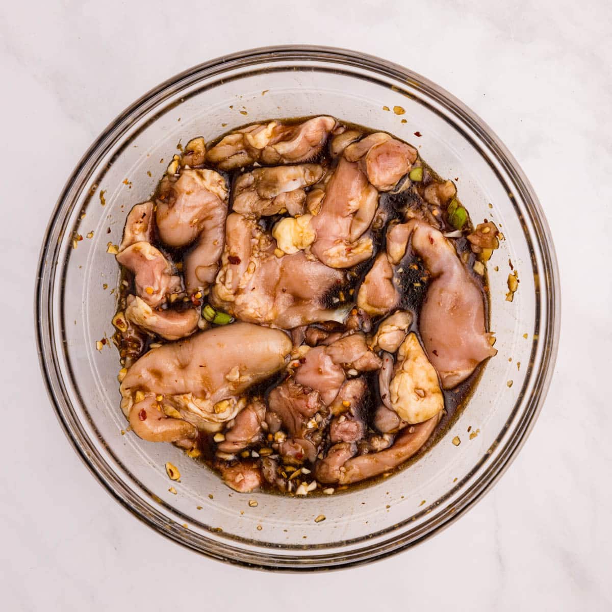 chicken thighs marinating in teriyaki sauce in a bowl