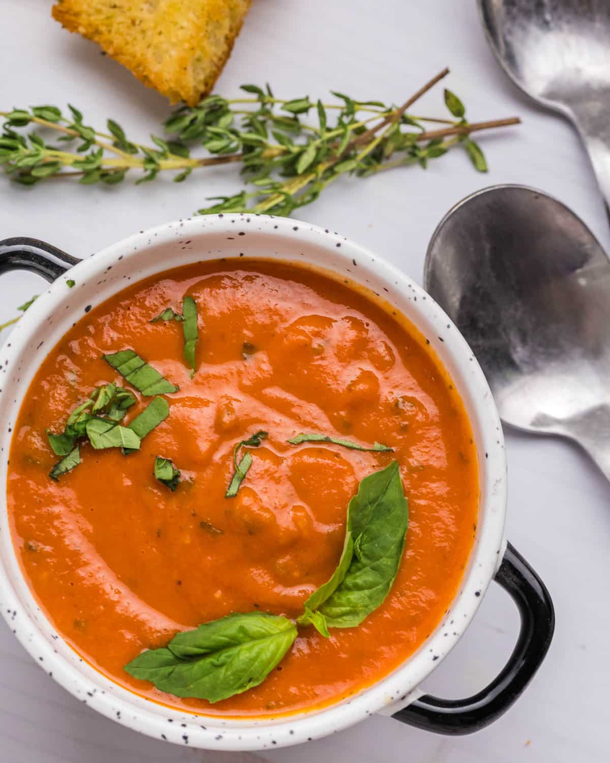 creamy tomato soup in a bowl with spoons