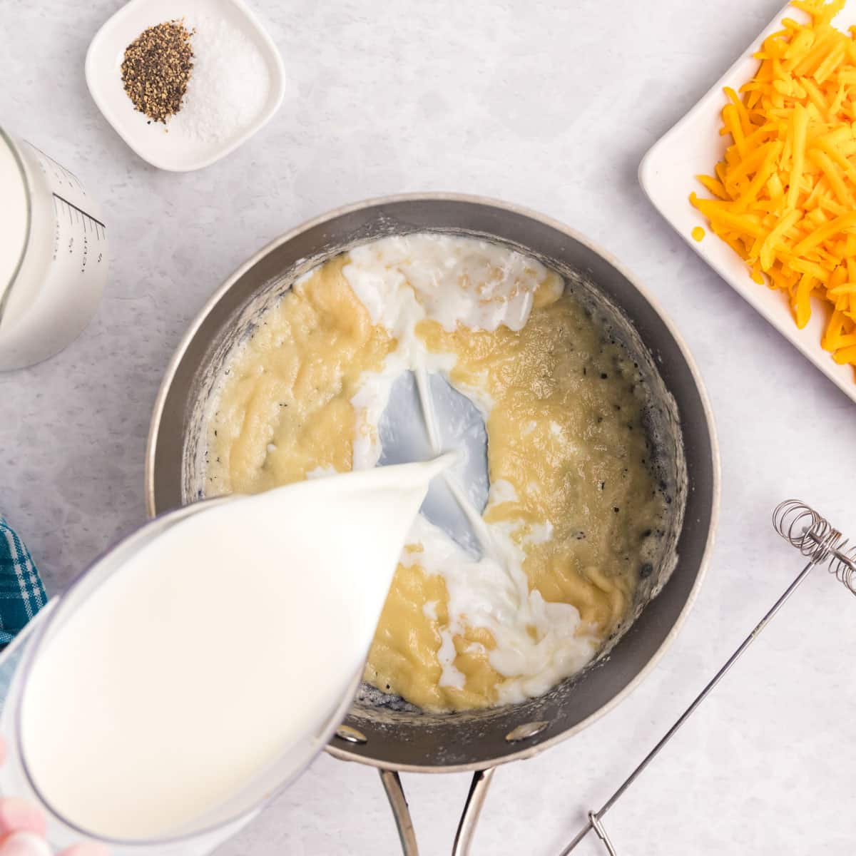 pouring milk into butter mixture in a saucepan