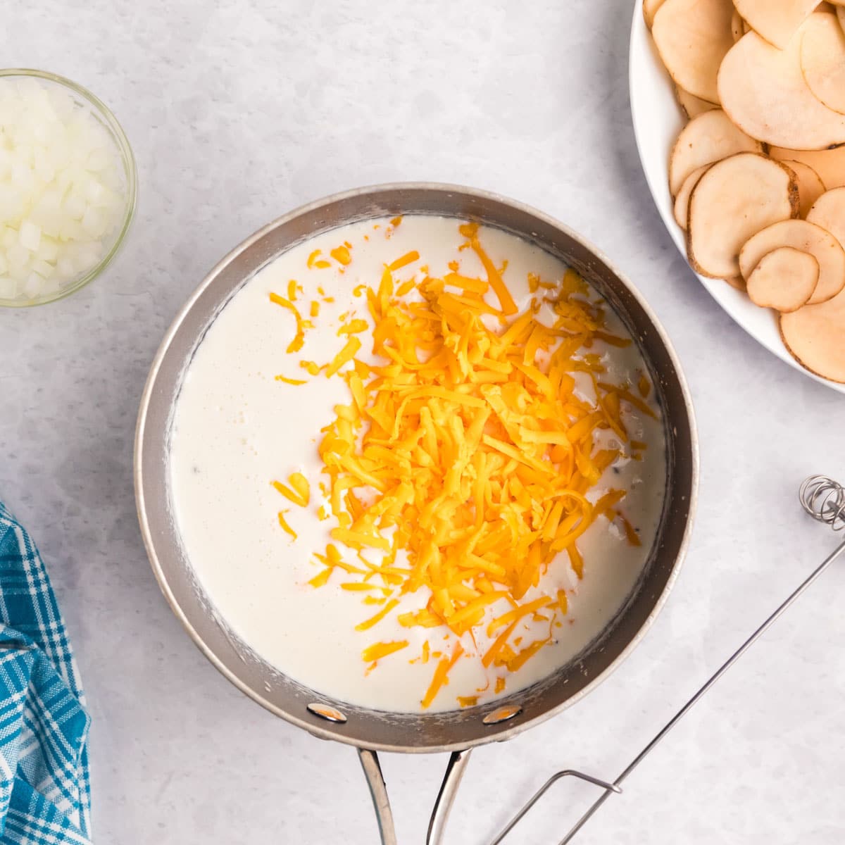 milk in a saucepan with shredded cheese