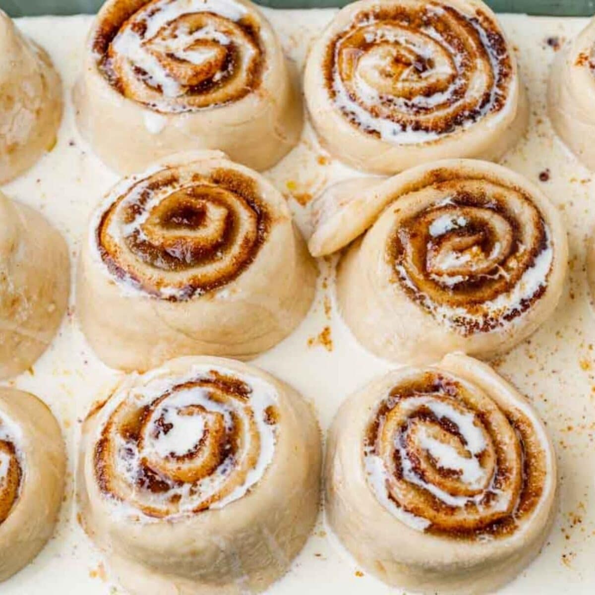 overhead view of unbaked cinnamon rolls with heavy cream over the top