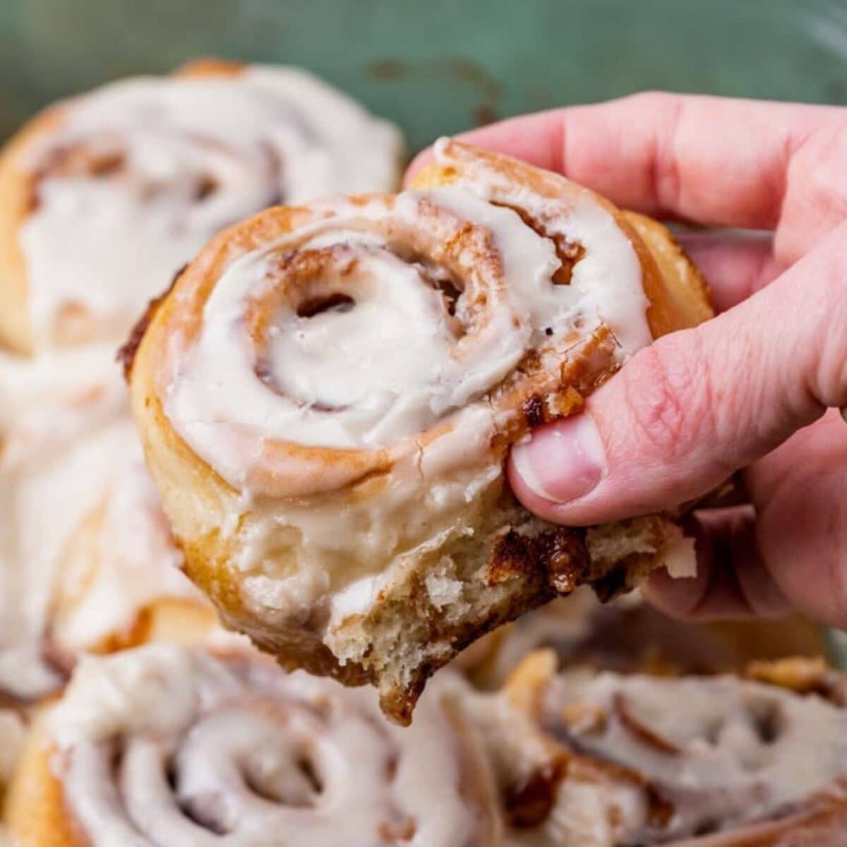 a hand holding a cinnamon roll