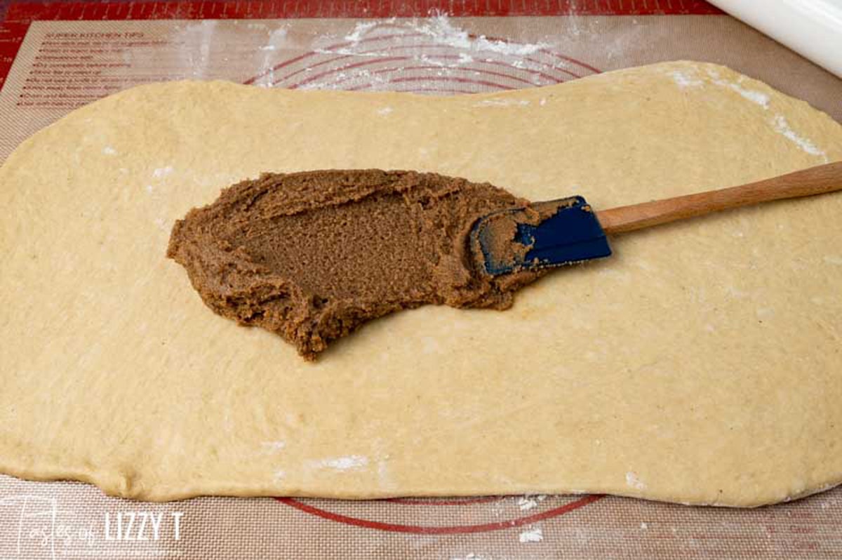 spreading cinnamon filling on bread dough