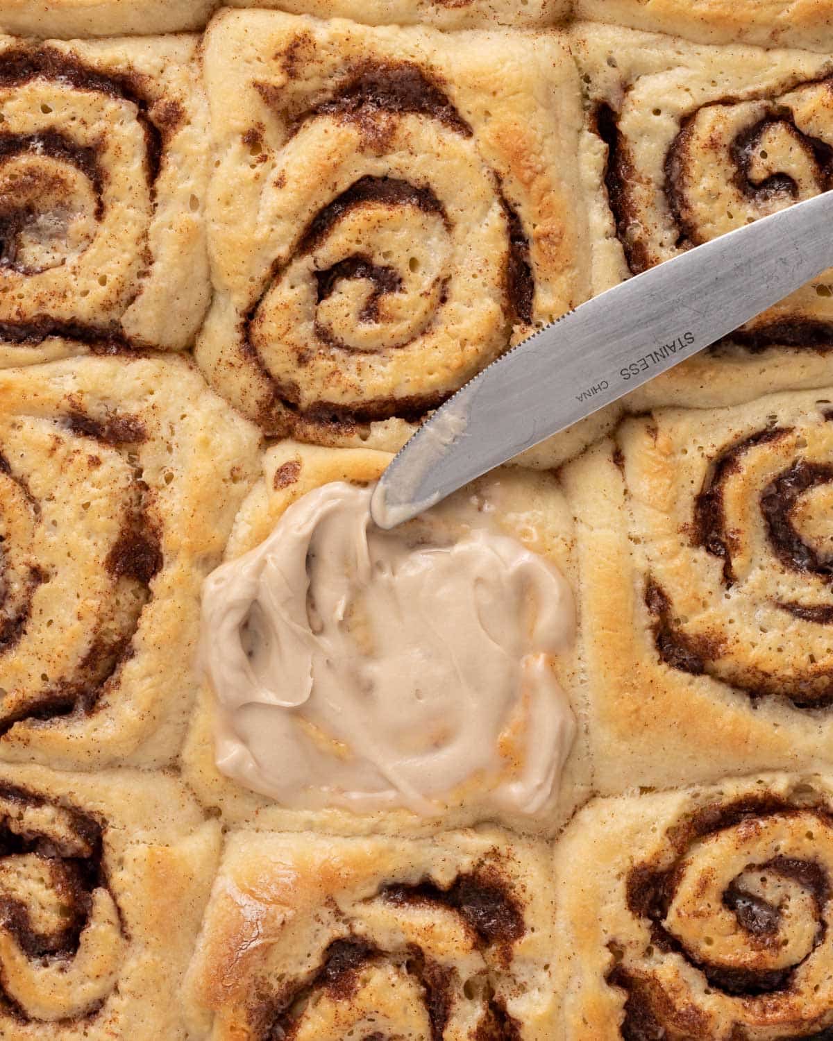 spreading icing on cinnamon rolls