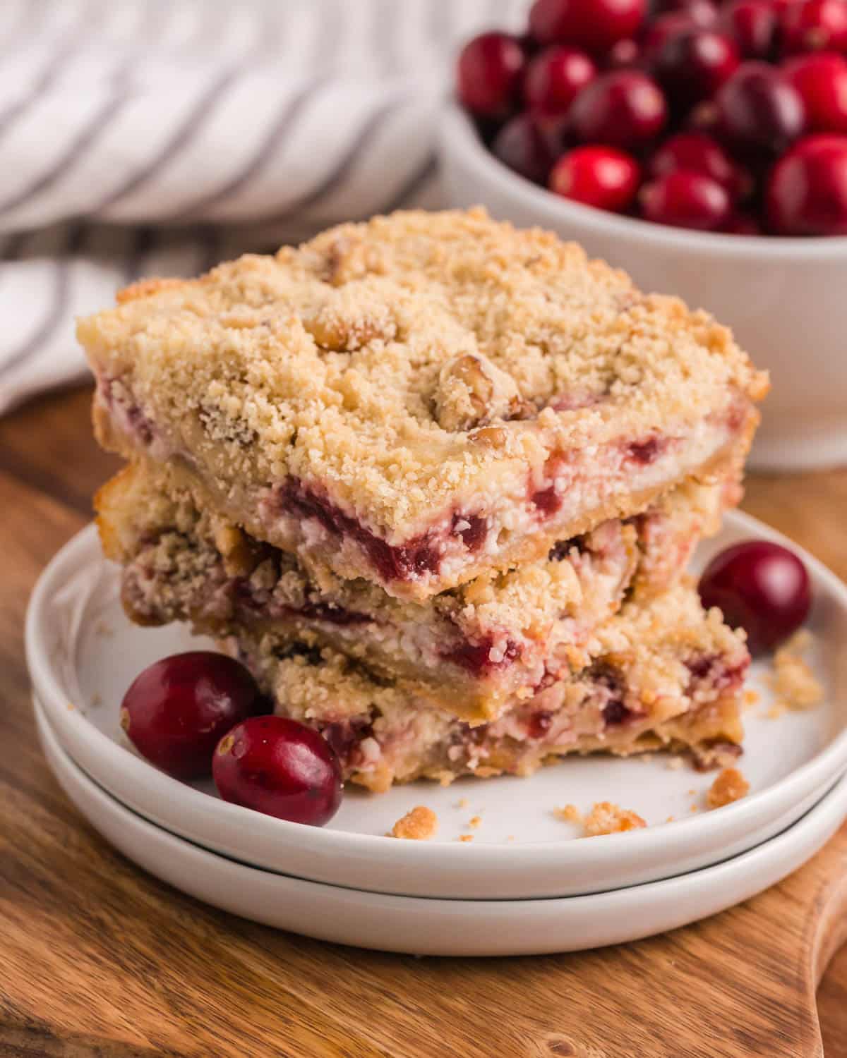 3 cranberry cream cheese bars stacked on a plate