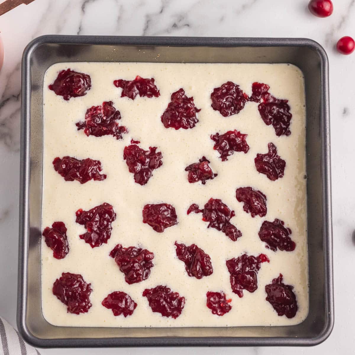 unbaked cream cheese bars with dollops of cranberry sauce on top