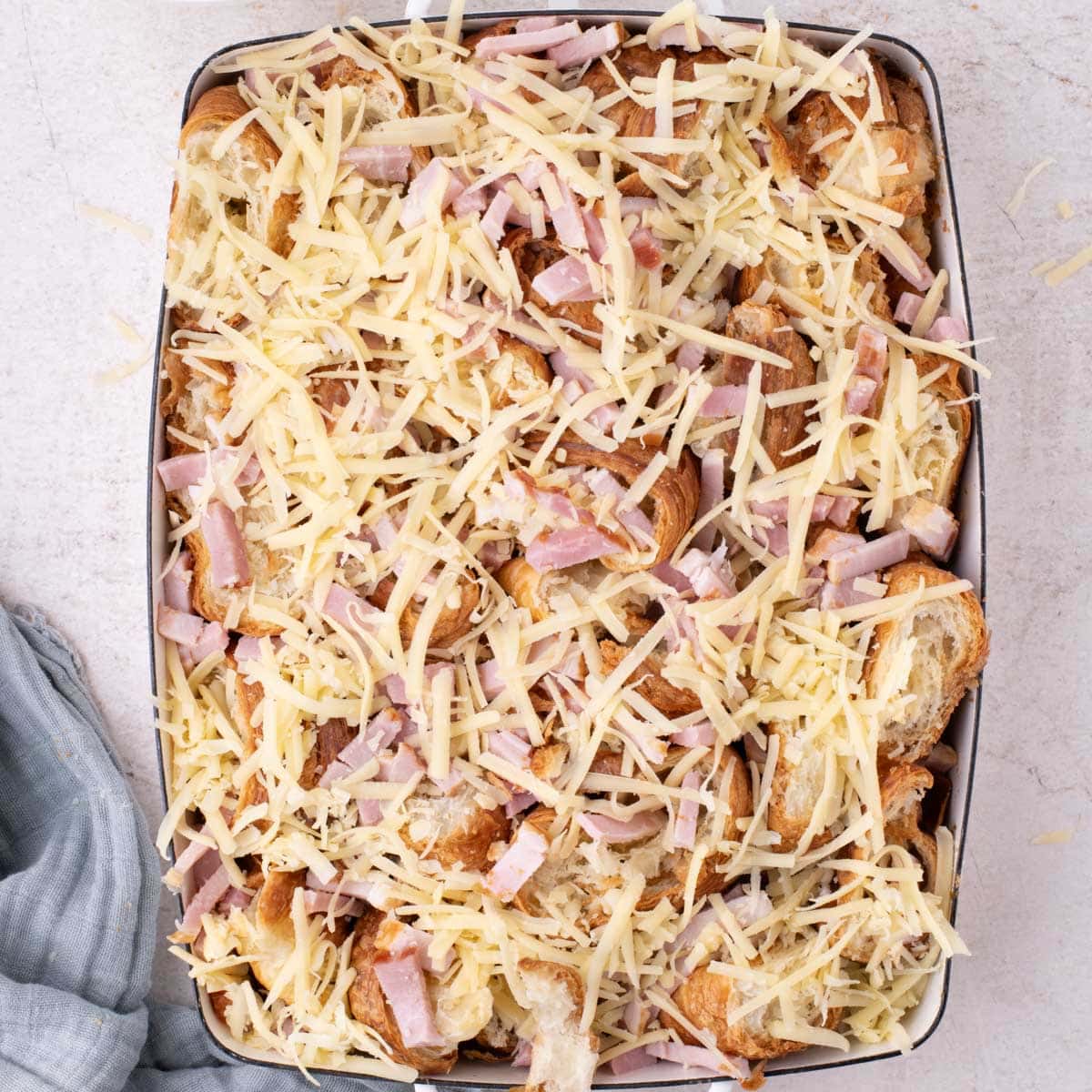 croissants with ham and cheese over the top in a baking dish