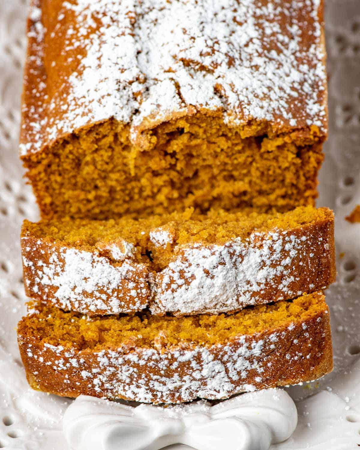 a sliced loaf of pumpkin bread with powdered sugar on top