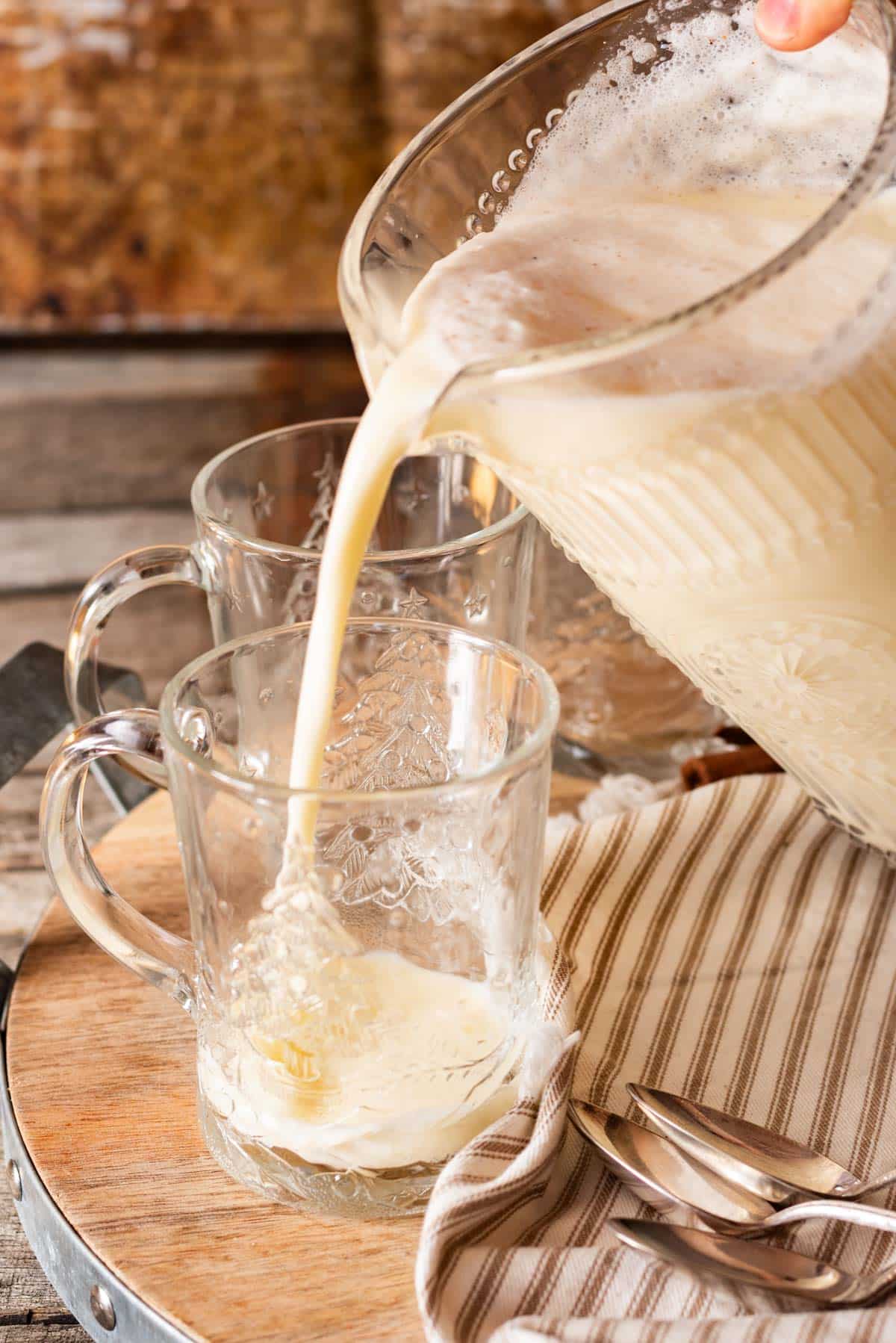 pouring eggnog into a glass mug