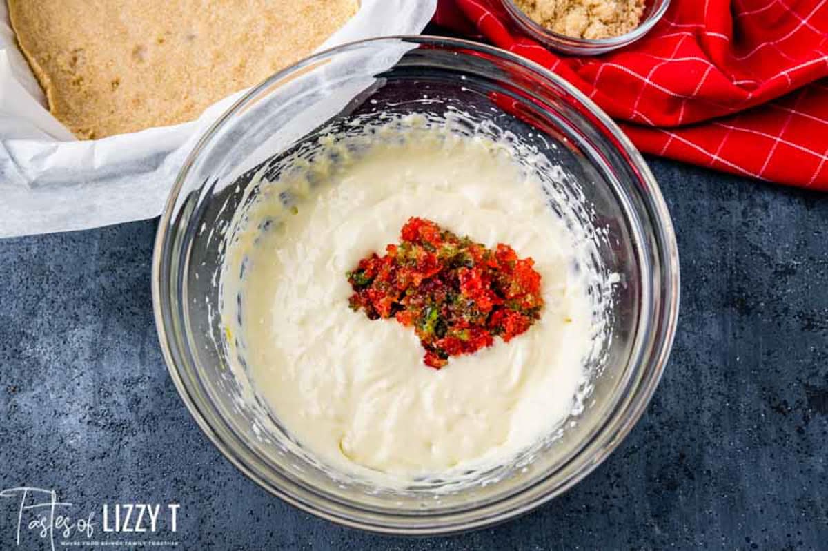 chopped candied cherries over cheesecake batter in a bowl