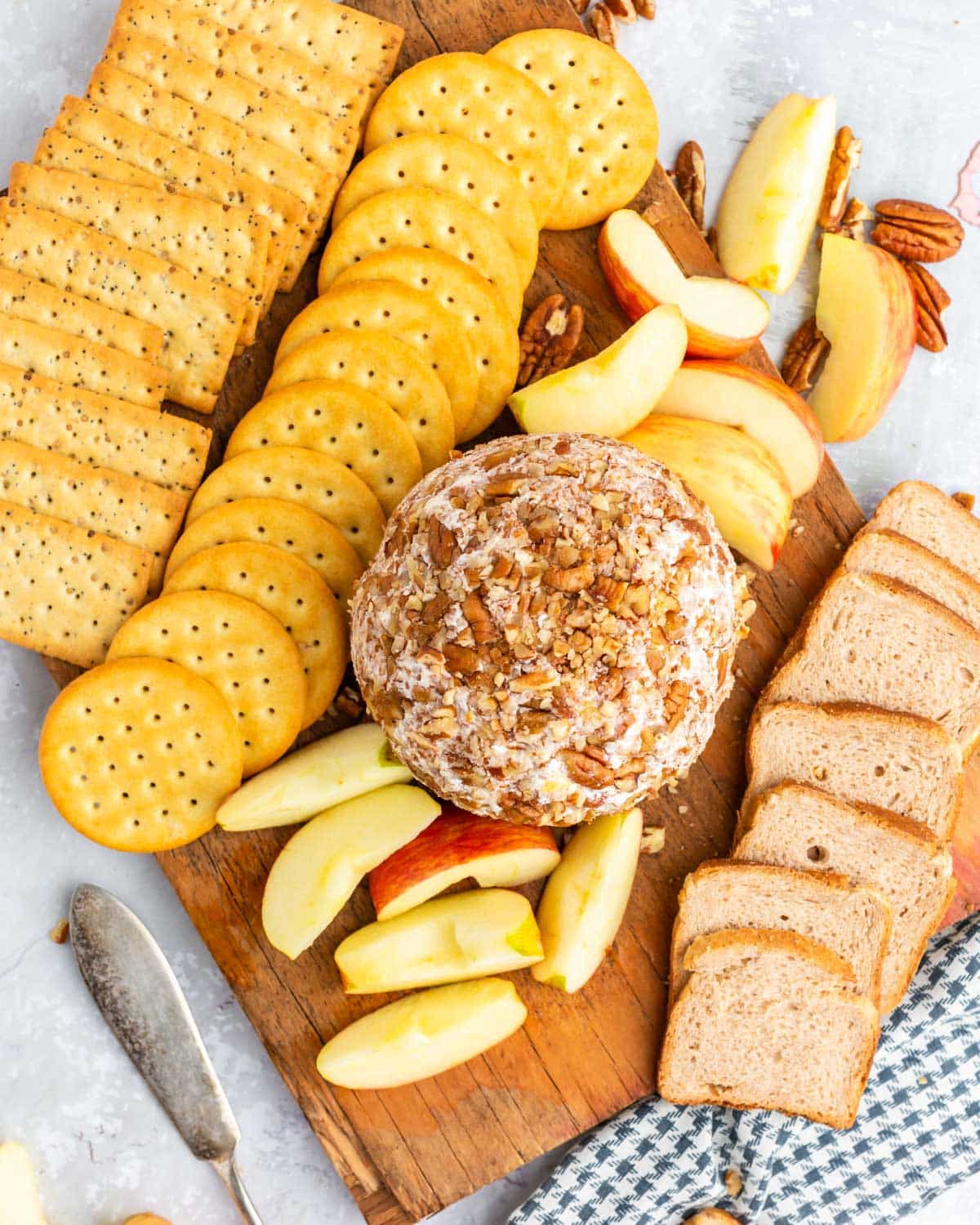 cheese ball on a board with apples, crackers and bread