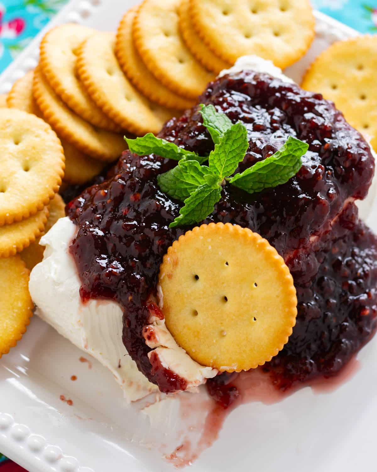 cream cheese with raspberry jam on top on a plate with a cracker in it