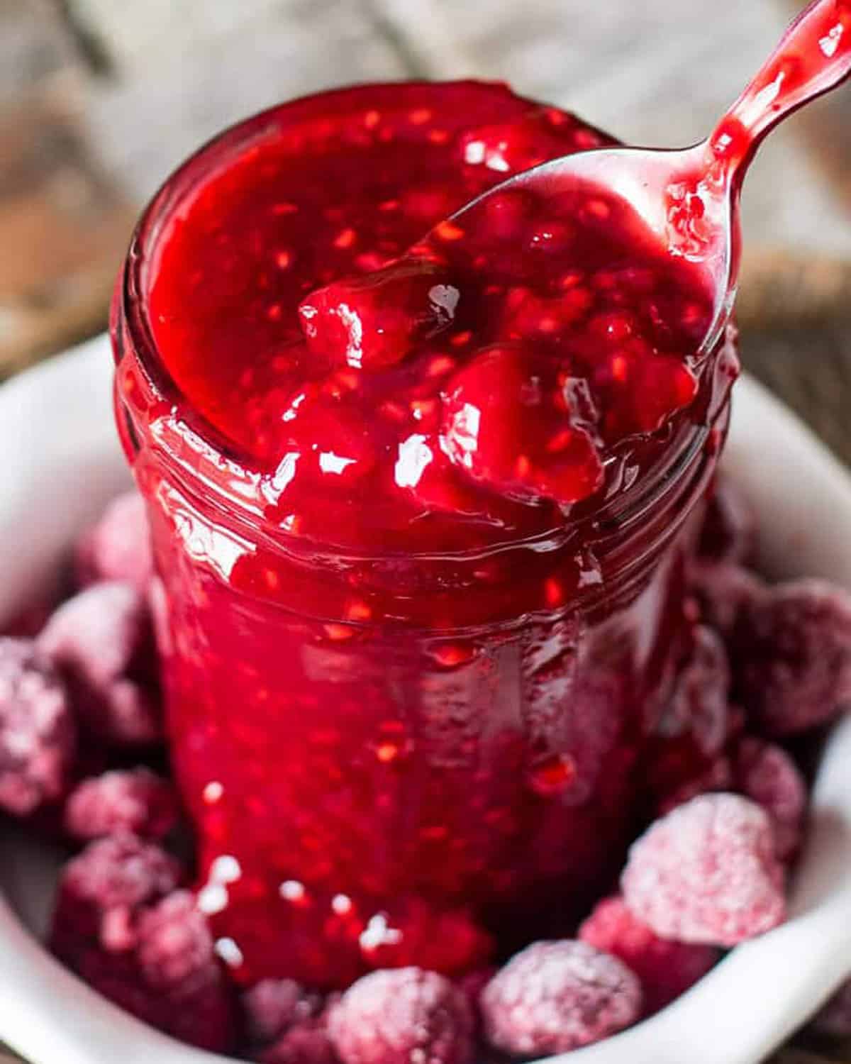 raspberry sauce in a jar with a spoon