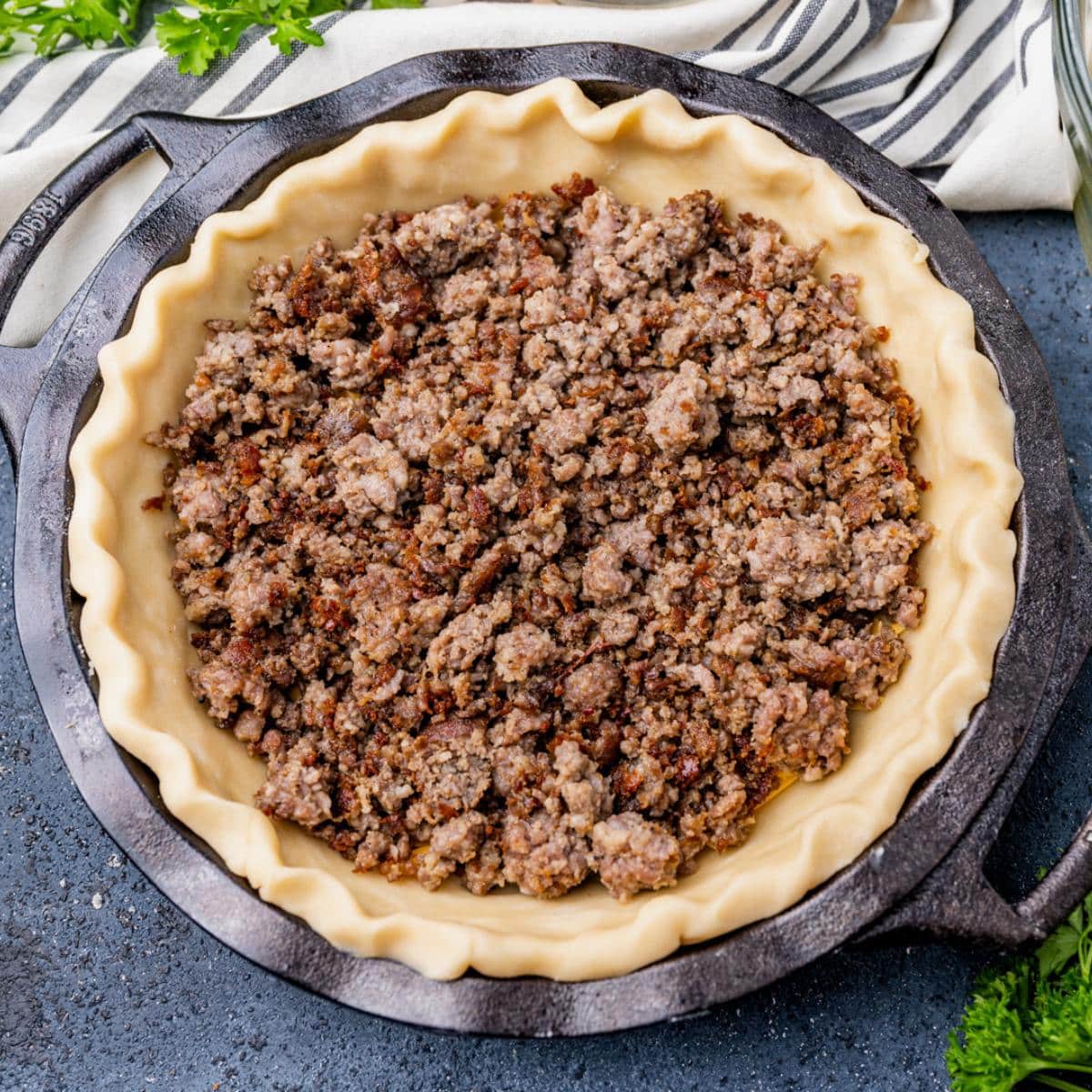 browned sausage in an unbaked pie shell