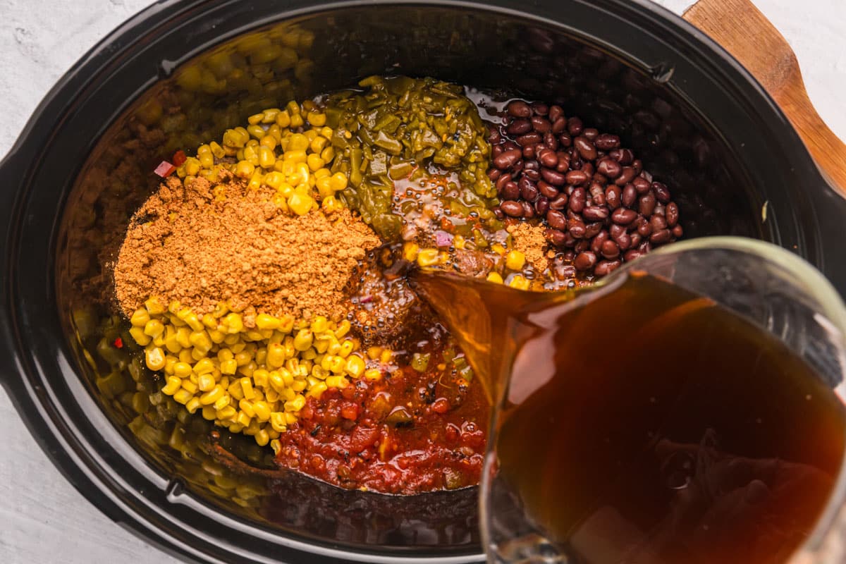 pouring beef broth into a slow cooker liner