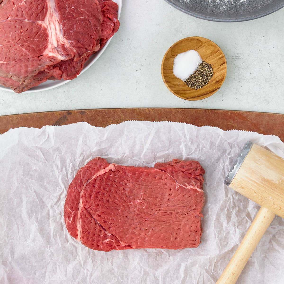 an uncooked steak pounded on a table