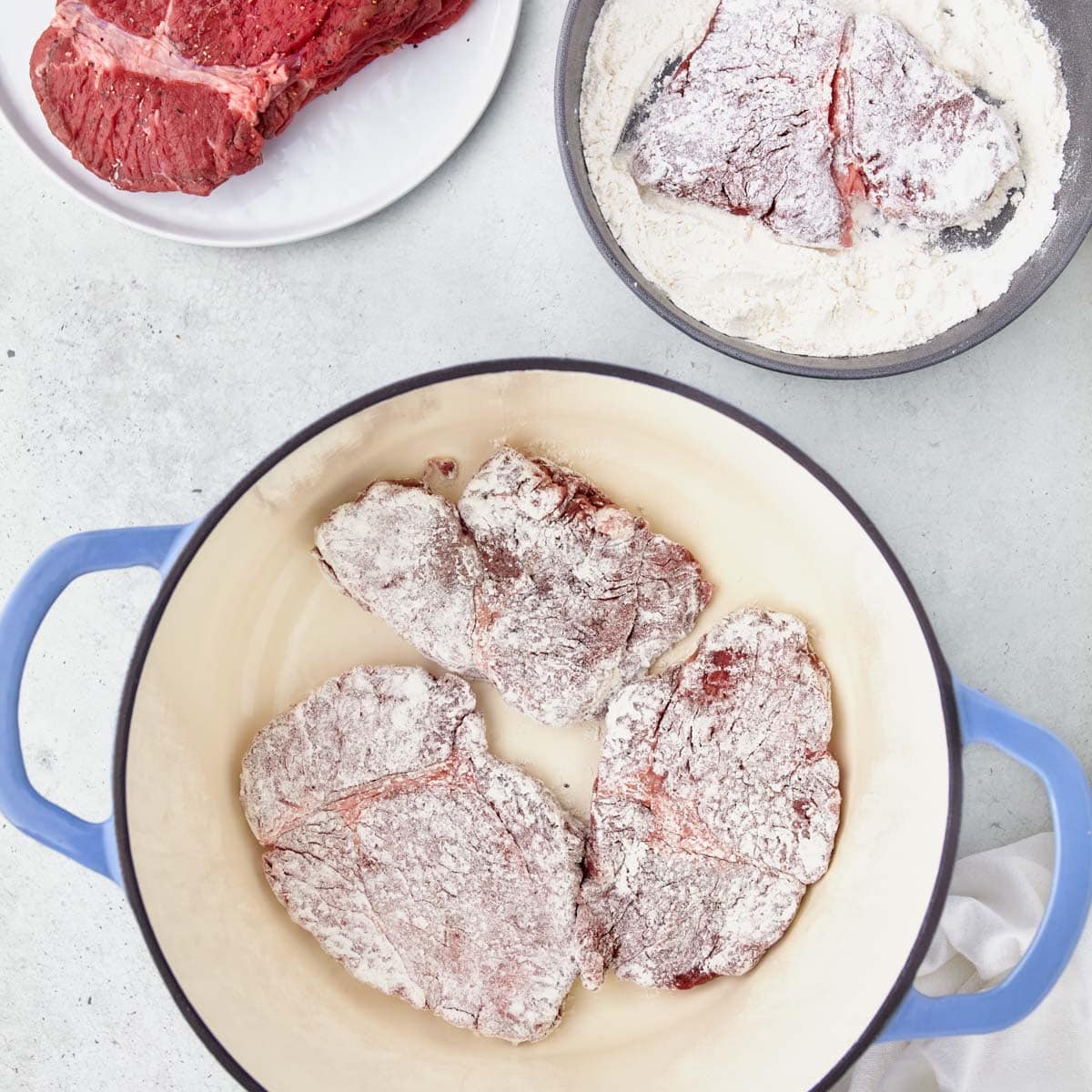 floured steaks in a dutch oven