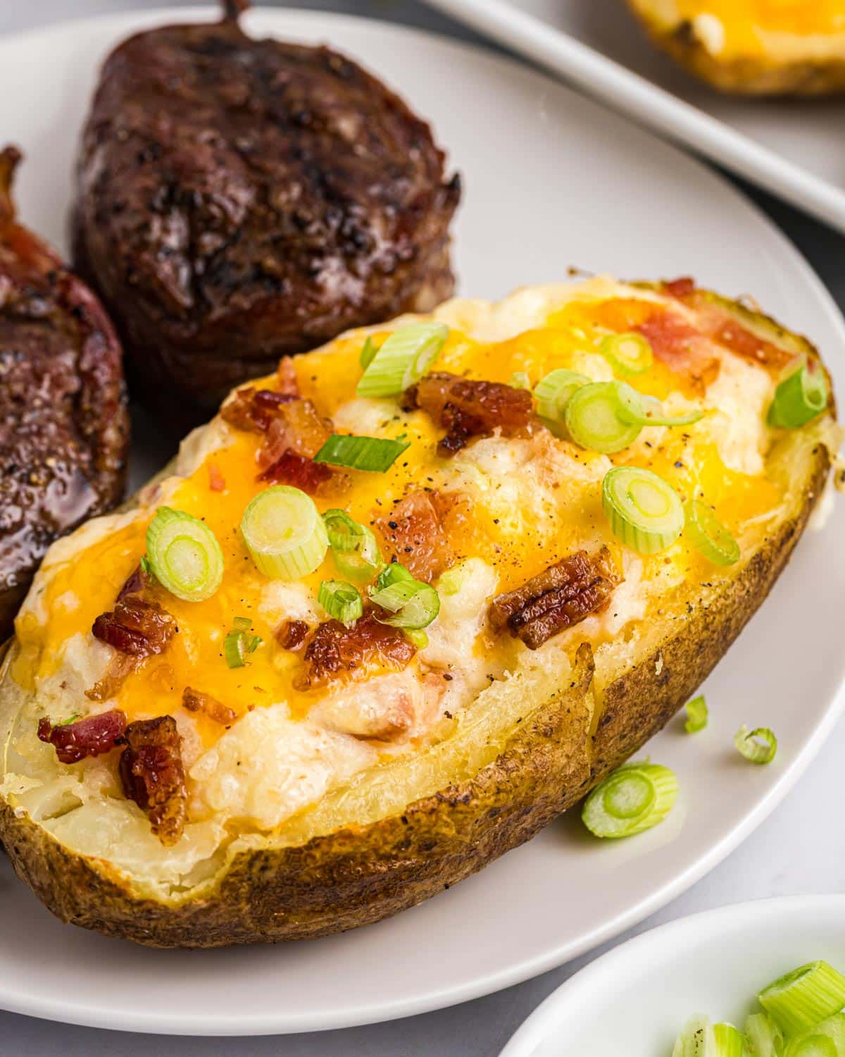 a twice baked potato on a plate with steak