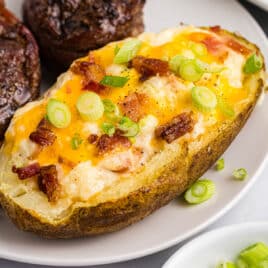 a twice baked potato on a plate with steak