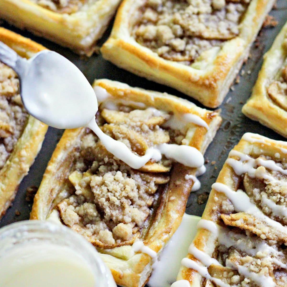 drizzling powdered sugar glaze on a apple danish