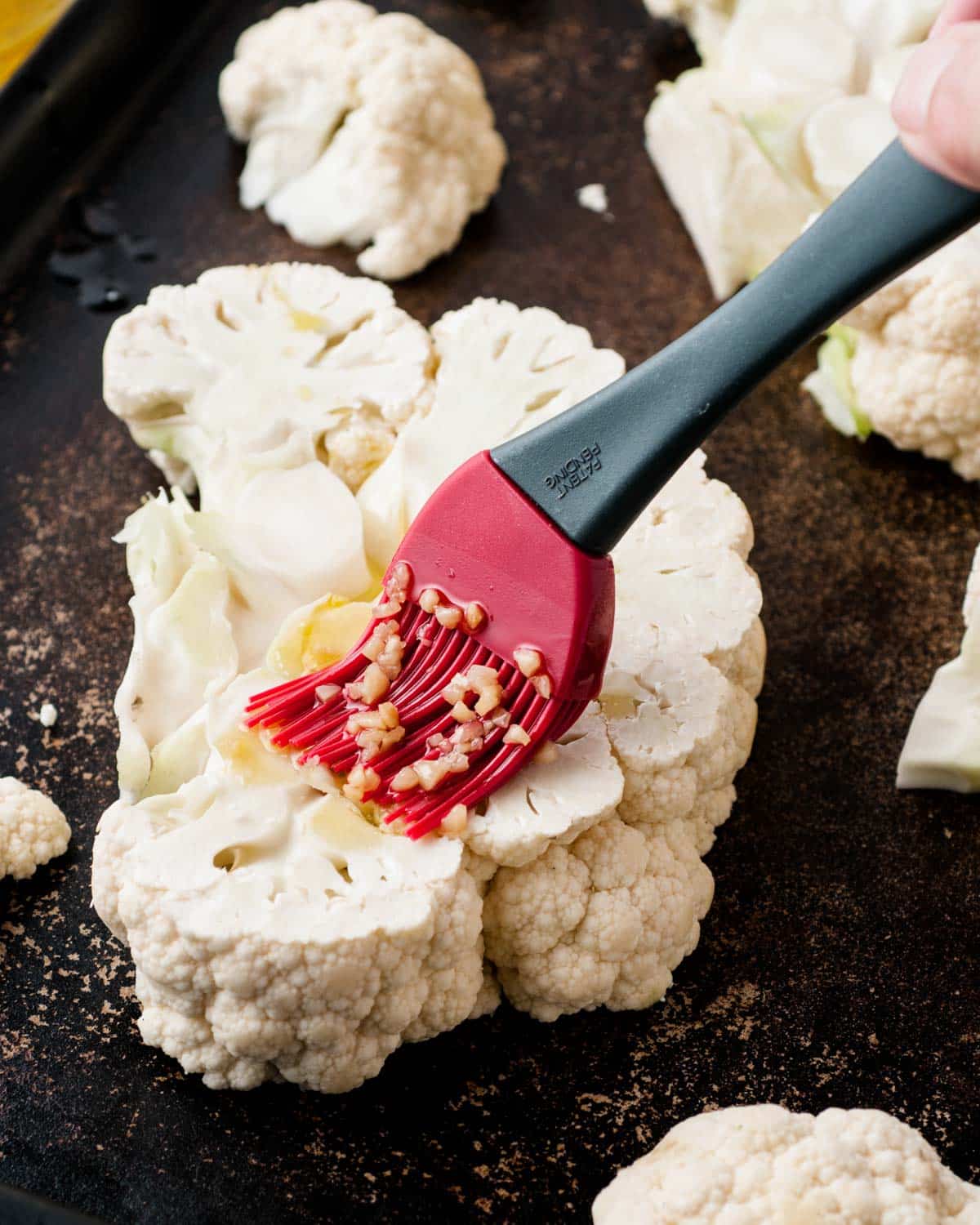 brushing olive oil on a slice of cauliflower